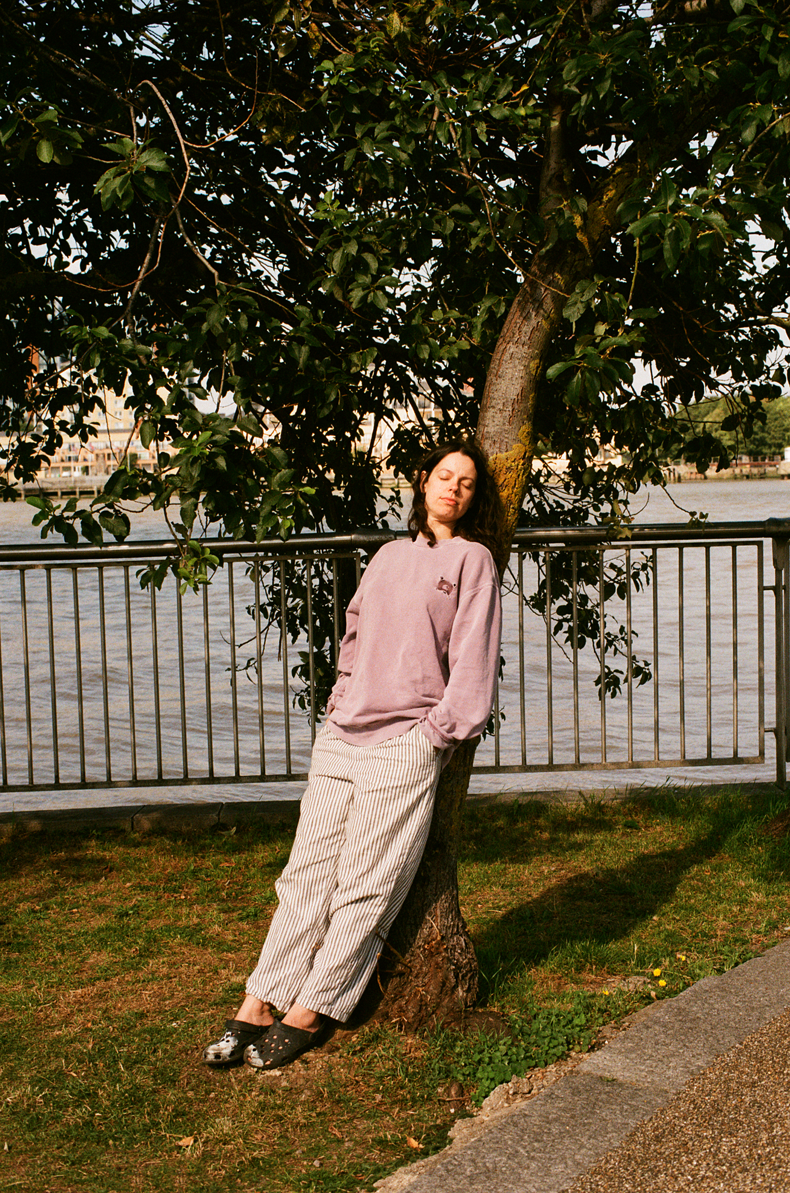 Tirzah leans back against tree