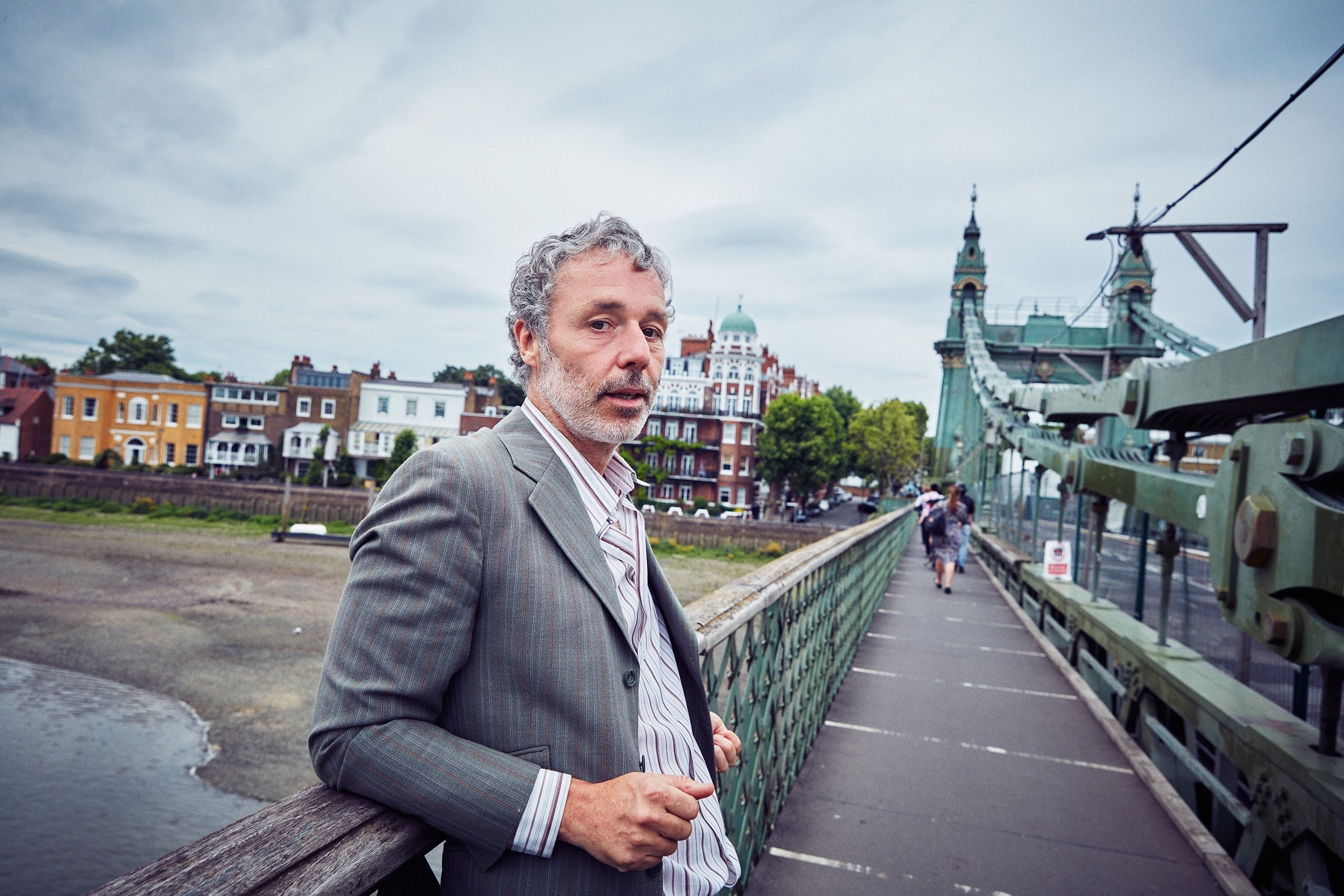 Baxter Dury leans on the side of Hammersmith Bridge, London