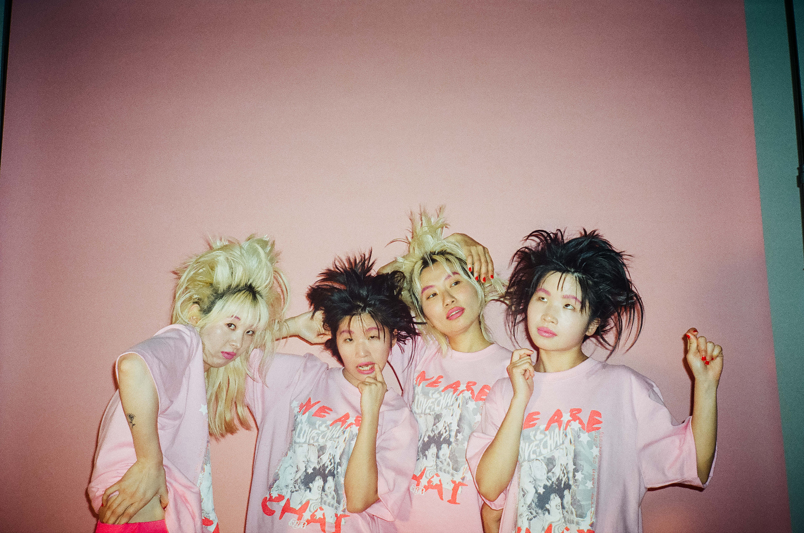 The 4 members of CHAI stood side by side against a pale pink backdrop